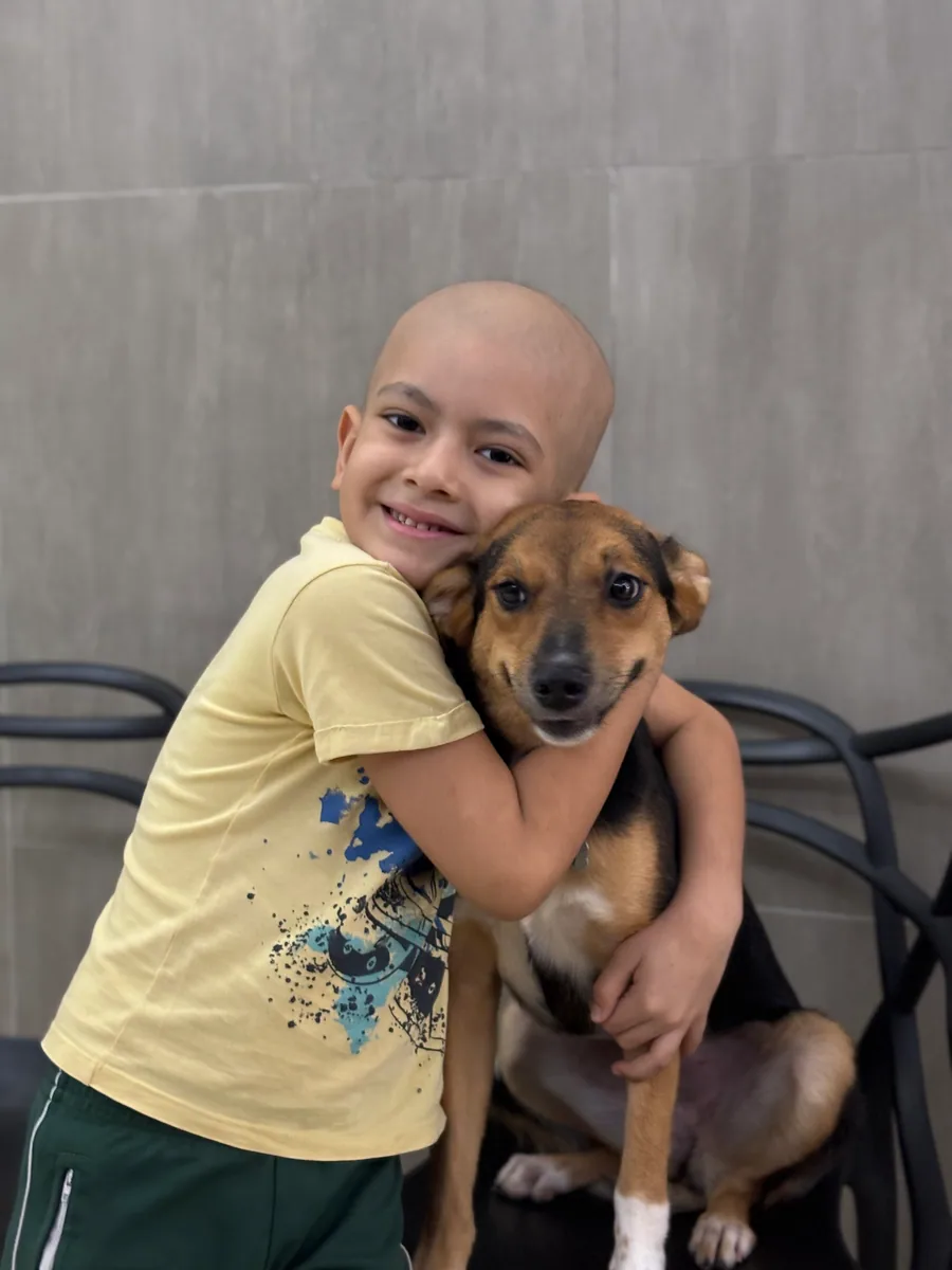 Criança abraçando carinhosamente um cachorro no PetCampos